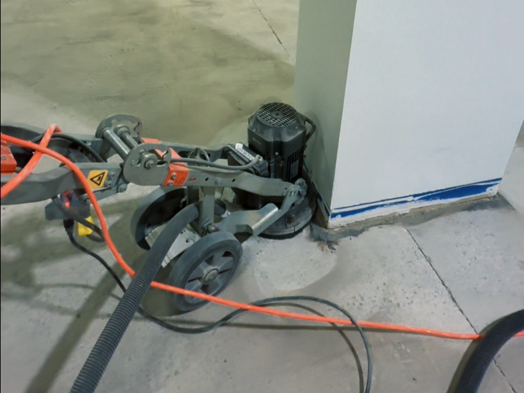 Industrial concrete grinding machine being used by The Deconstructors for precision edge work and surface preparation on a commercial floor in British Columbia.